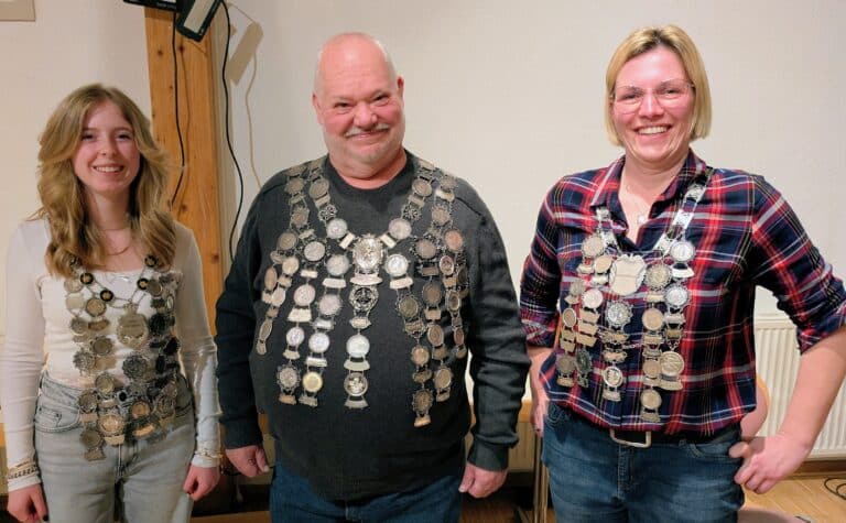 Eine Frau, ein Mann und ein Mädchen stehen nebeneinander und lächeln in die Kamera. Alle drei tragen eine Schützenkette um den Hals.